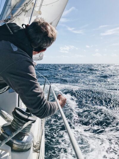 Ein Mann beim Segeltrimm auf dem offenen blauen Meer
