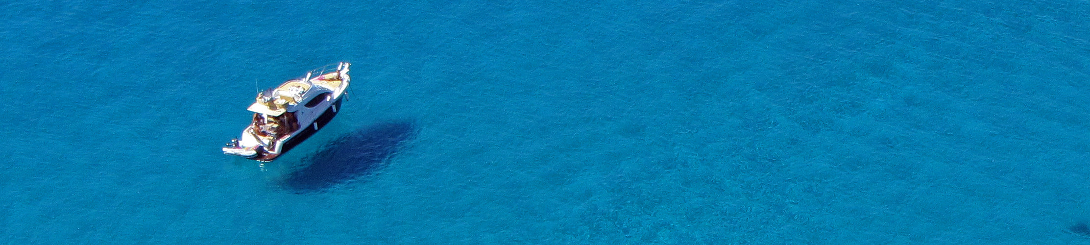 Ein kleines Boot schwebt bei Sonnenschein auf klarem blauem Wasser